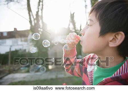 Picture - Boy blowing bubbles with wand, close up. Fotosearch