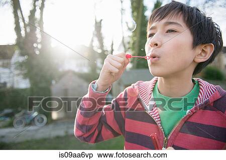 Stock Photography - Boy blowing bubbles with wand, close up. Fotosearch