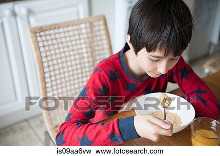 Boy eating breakfast cereal at table View Large Photo Image Stock Photo - Boy eating breakfast cereal at table. Fotosearch