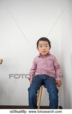 Stock Photography - Boy sitting on stool, portrait. Fotosearch