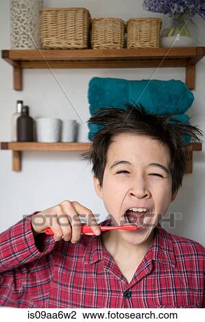 Stock Image - Boy yawning and brushing teeth, portrait. Fotosearch