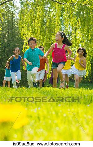 Stock Image - Children running on grass. Fotosearch