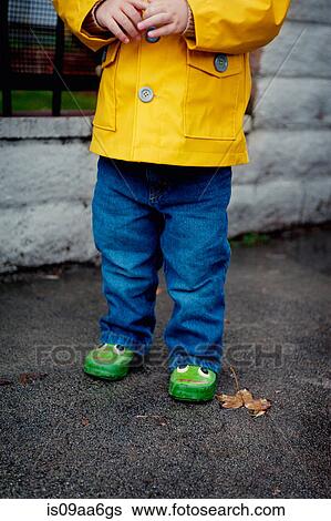 Stock Photograph - Close up of female toddler wearing yellow raincoat. Fotosearch