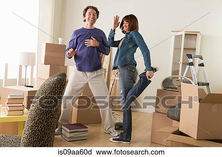 Stock Image - Couple having fun dancing whilst moving house. Fotosearch