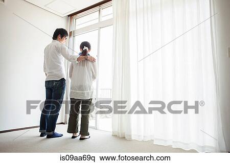Couple standing by window View Large Photo Image Stock Photography - Couple standing by window. Fotosearch