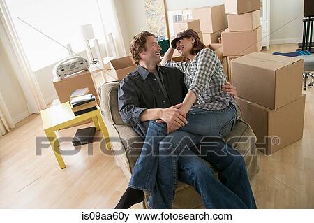 Couple taking a break in armchair whilst moving home View Large Photo Image Stock Photo - Couple taking a break in armchair whilst moving home. Fotosearch