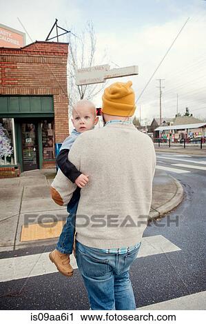Stock Image - Father carrying young son across pedestrian crossing. Fotosearch
