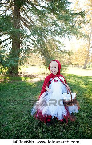 Stock Image - Female toddler in woods dressed up in red riding hood costume. Fotosearch
