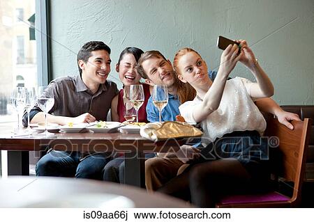 Four friends photographing themselves in restaurant View Large Photo Image Stock Image - Four friends photographing themselves in restaurant. Fotosearch