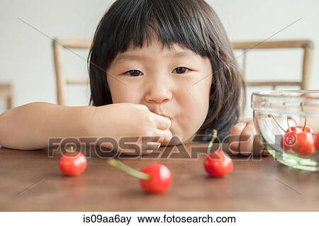 Stock Photo - Girl eating cherries, portrait. Fotosearch