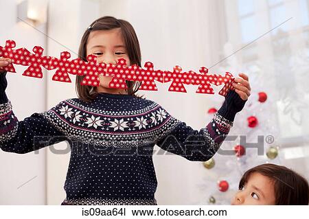 Stock Image - Girl holding Christmas decorations. Fotosearch