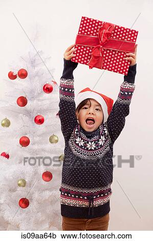 Girl holding up Christmas present, portrait View Large Photo Image Stock Image - Girl holding up Christmas present, portrait. Fotosearch