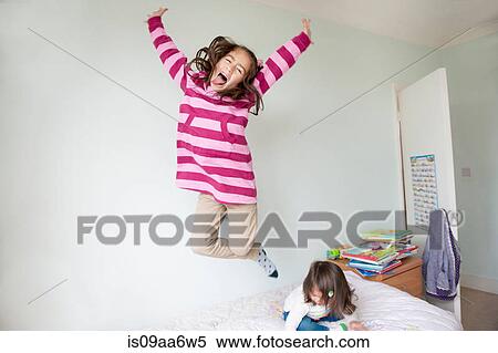 Stock Photography - Girl jumping on bed and pulling face. Fotosearch