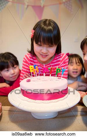 Girl looking at birthday candles on cake View Large Photo Image Stock Image - Girl looking at birthday candles on cake. Fotosearch