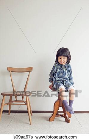 Stock Photograph - Girl sitting on stool, portrait. Fotosearch