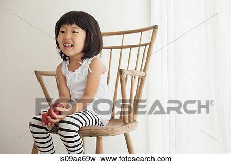 Stock Photo - Girl sitting on wooden chair, portrait. Fotosearch