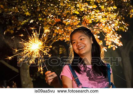 Girl with sparkler at night View Large Photo Image Stock Photograph - Girl with sparkler at night. Fotosearch