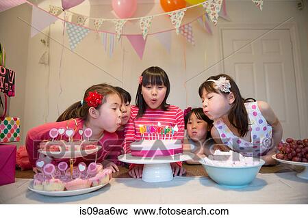 Girls blowing out birthday candles on cake View Large Photo Image Stock Image - Girls blowing out birthday candles on cake. Fotosearch