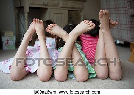 Picture - Girls lying on floor together with feet up. Fotosearch
