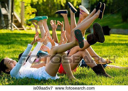 Stock Photo - Girls lying on grass with arms and legs raised. Fotosearch