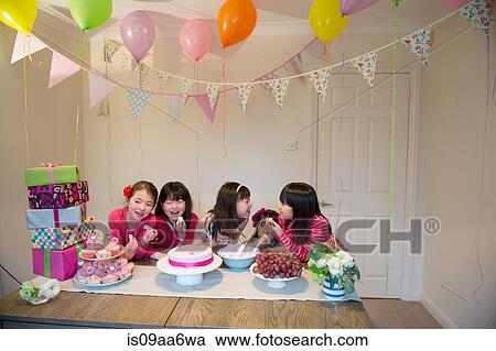 Stock Image - Girls sharing birthday cake at party. Fotosearch