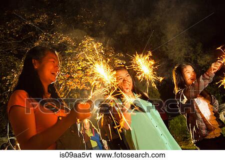 Stock Photograph - Girls with sparklers at night. Fotosearch