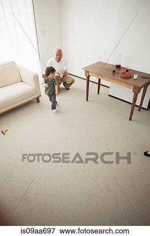 Stock Photo - Grandfather and grandson in living room, high angle. Fotosearch
