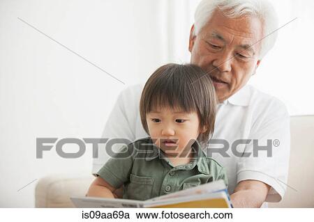 Stock Image - Grandfather reading to grandson. Fotosearch
