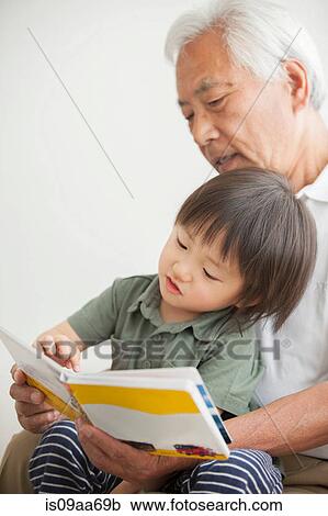 Stock Image - Grandfather reading to grandson. Fotosearch