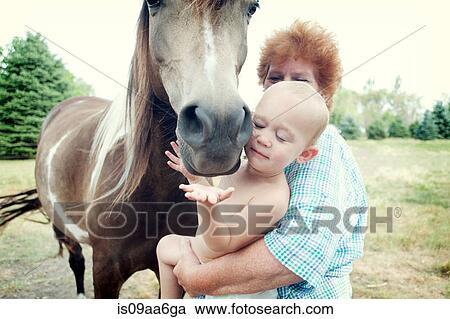 Stock Image - Grandmother and toddler with horse. Fotosearch