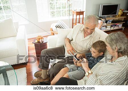 Stock Photo - Grandparents sitting with grandson and looking at digital tablet. Fotosearch