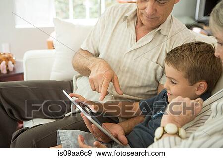 Stock Photo - Grandparents sitting with grandson and looking at digital tablet. Fotosearch