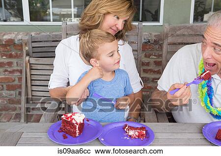 Grandson and mother watching senior man eat birthday cake View Large Photo Image Stock Image - Grandson and mother watching senior man eat birthday cake. Fotosearch