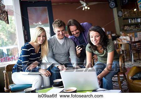 Stock Image - Group of people gathered around computer in cafe. Fotosearch