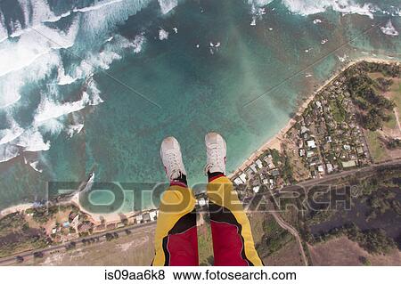 Stock Photo - Legs and feet of skydiver above coastline. Fotosearch