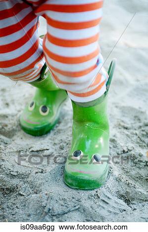 Stock Image - Legs of young male toddler wearing smiley wellington boots. Fotosearch