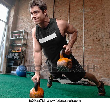 Stock Image - Male bodybuilder lifting kettlebells. Fotosearch
