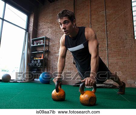 Stock Image - Male bodybuilder using kettlebells. Fotosearch