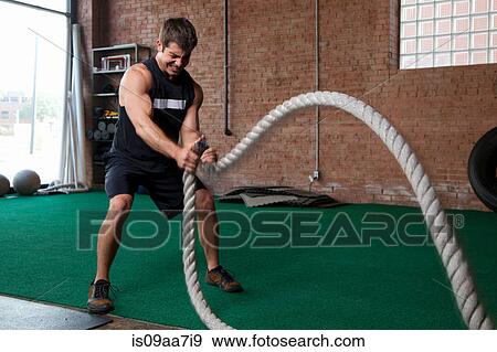 Stock Photo - Male bodybuilder using ropes in gym. Fotosearch