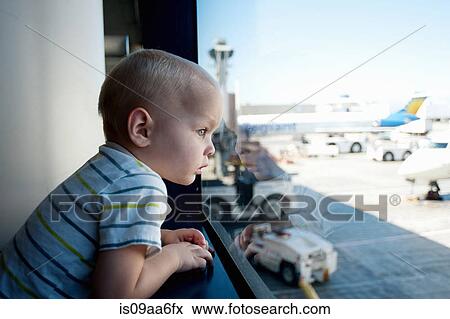 Stock Photo - Male toddler looking out of window at Los Angeles airport. Fotosearch