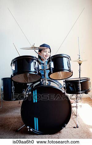 Stock Image - Male toddler playing on drum kit. Fotosearch
