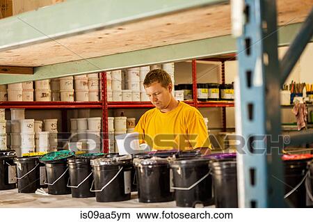 Picture - Man checking ink in screen print workshop. Fotosearch