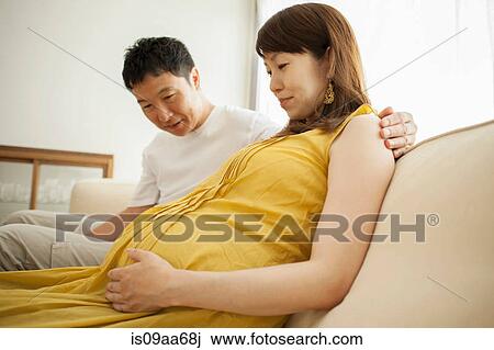 Man looking at pregnant woman's stomach on sofa View Large Photo Image Stock Image - Man looking at pregnant woman's stomach on sofa. Fotosearch