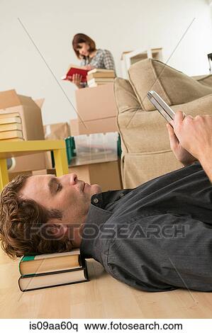 Stock Photography - Man lying on floor looking at digital tablet whilst moving. Fotosearch