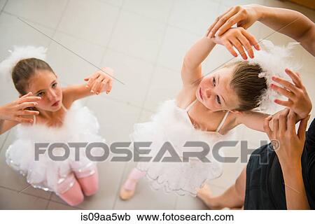 Stock Image - Mature ballet teacher arranging ballerina's hands. Fotosearch