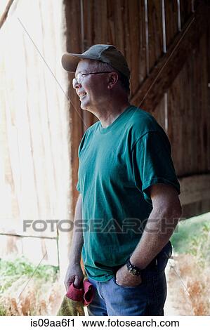 Stock Image - Mature farmer looking away, smiling. Fotosearch