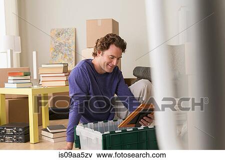Mature man sitting on floor looking at unpacked picture View Large Photo Image Stock Photo - Mature man sitting on floor looking at unpacked picture. Fotosearch