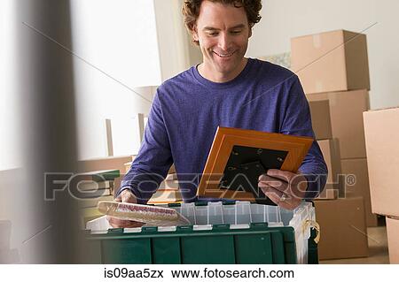 Mature man unpacking picture frame from crate View Large Photo Image Stock Photo - Mature man unpacking picture frame from crate. Fotosearch
