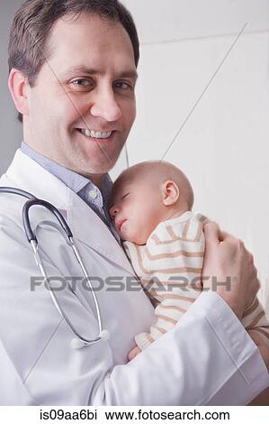 Mid adult doctor holding baby boy, portrait View Large Photo Image Stock Image - Mid adult doctor holding baby boy, portrait. Fotosearch