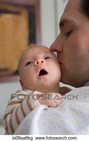 Stock Image - Mid adult father kissing baby boy. Fotosearch